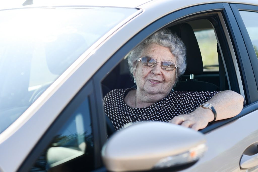 happy cheerful elderly senior woman driving her car