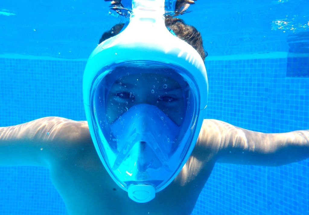 Child with full face snorkel in pool