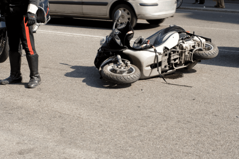 Motorcyclist standing next to motorcycle on ground