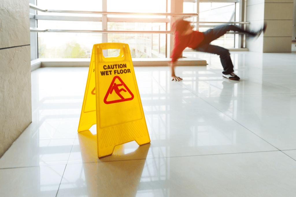 Man slips on floor next to caution wet floor sign