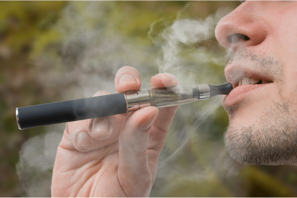 Young smoker is vaping e-cigarette or vaporizer