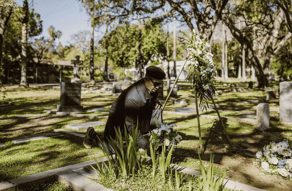 Photo of a man laying flowers at a cemetery
