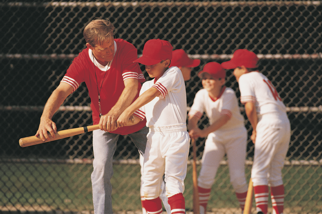 Coach helping youth baseball player