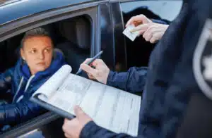 Man with clipboard speaking to woman in driver seat