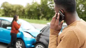 Man on his phone with a car crash in the background