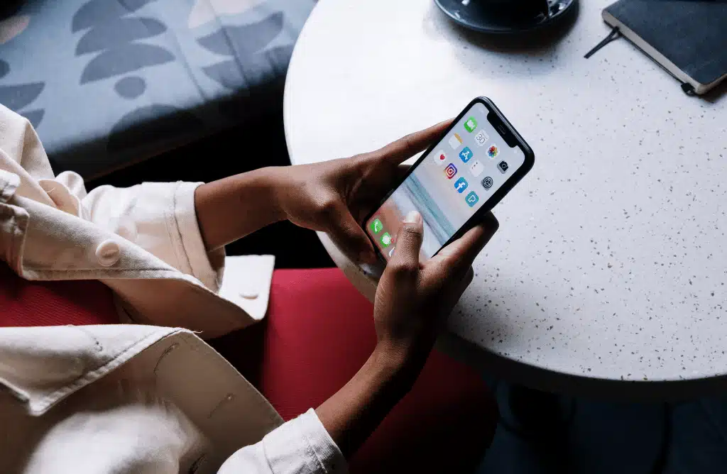 a person's hands holding a smartphone displaying various icons