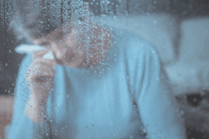 Elderly woman crying in window