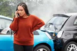 Woman upset on the phone with a car accident behind her