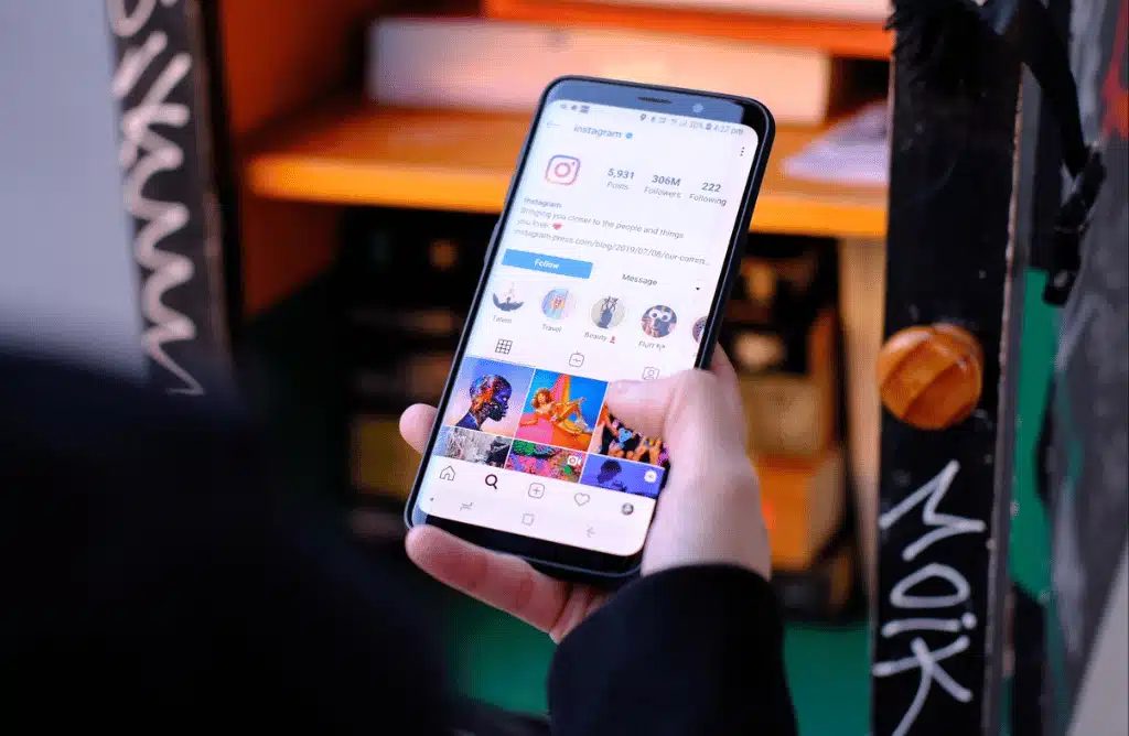 A person holding a smartphone and scrolling through the Instagram app