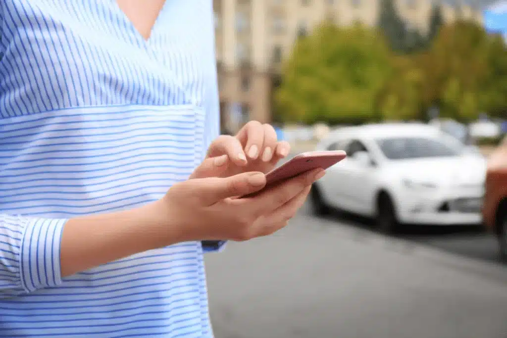 Woman calling an uber on her cell phone while on the street