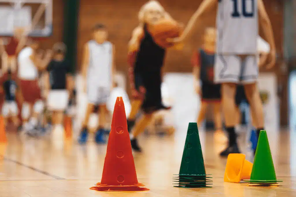 A blurred image of youth basketball players with four brightly colored training cones on the floor