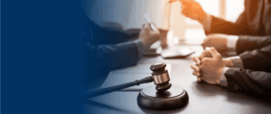 Closeup of gavel on table with lawyers conversing behind it