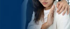A close-up of a woman with her hand up in a defensive gesture, recoiling from a man's hand on her shoulder