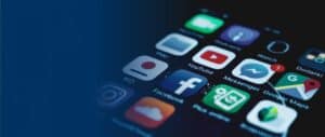 A close-up of a smartphone screen displaying various app icons, including the Facebook and Messenger app icons