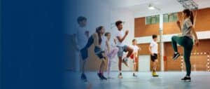 A gym teacher and a group of children raising their knees in a coordinated exercise