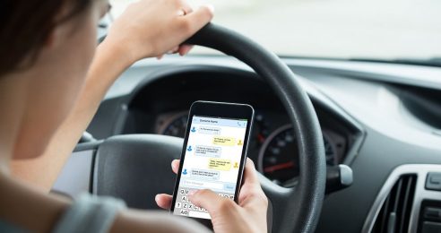 Close-up Of Woman Sitting Inside Car Typing Text Message On Mobile Phone