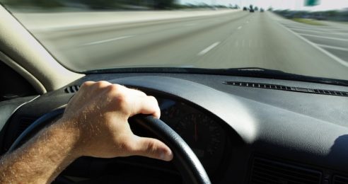 Hand on car steering wheel